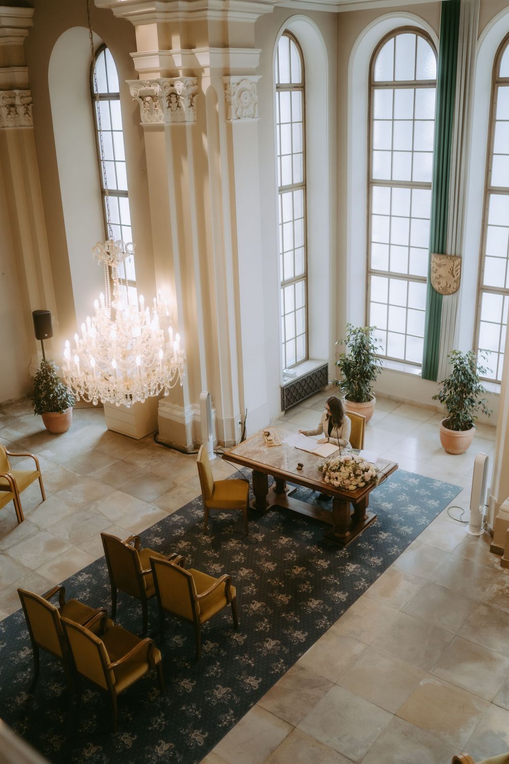 Elegant ballroom interior with crystal chandeliers, tall windows, and ornate architectural details.