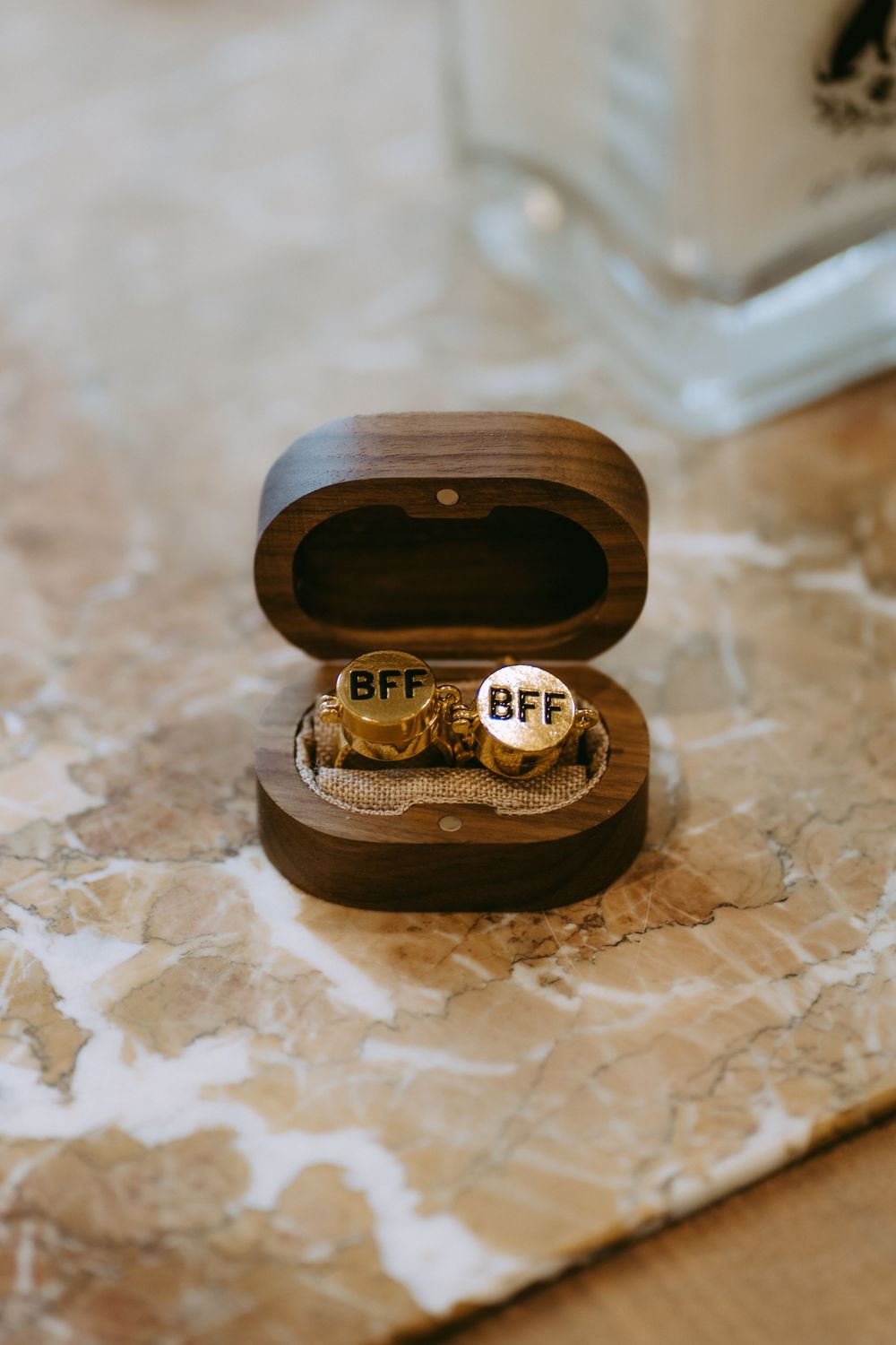 Wedding rings displayed in brown wooden boxes on marble surface.