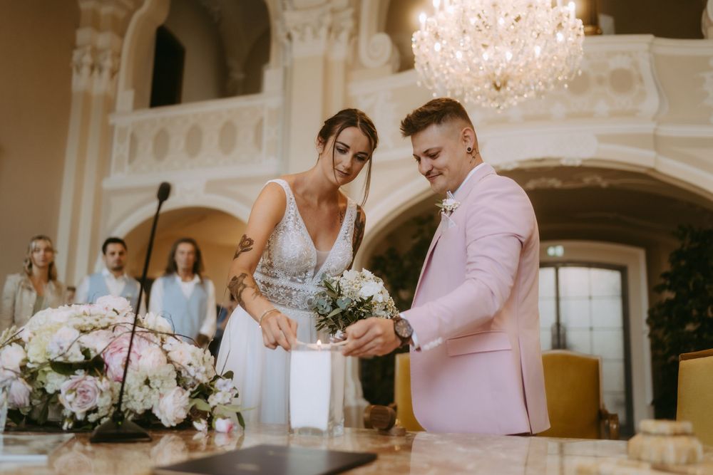 Wedding celebration in ornate ballroom with crystal chandeliers and guests in formal attire.