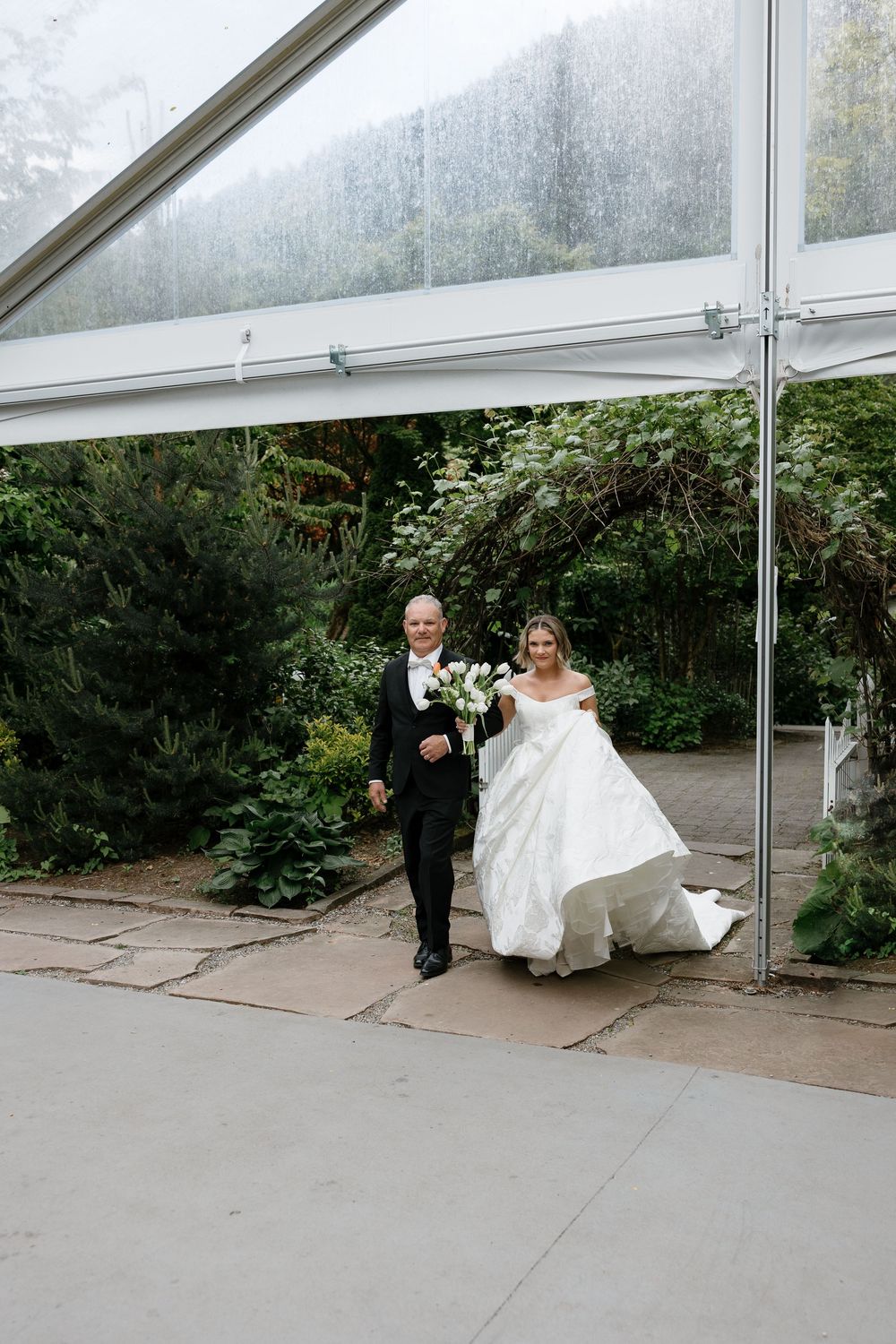 Wedding ceremony sequence under a clear tent with white decor and greenery backdrop.