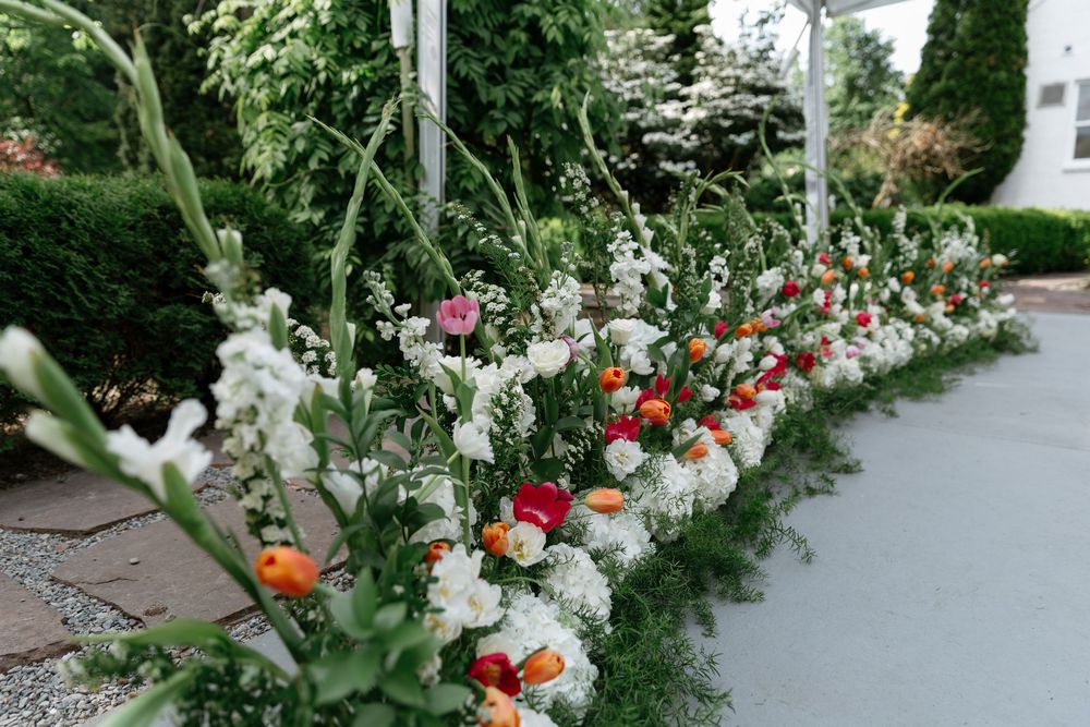 Garden pathway lined with colorful flowers and greenery creates a beautiful outdoor wedding setting.