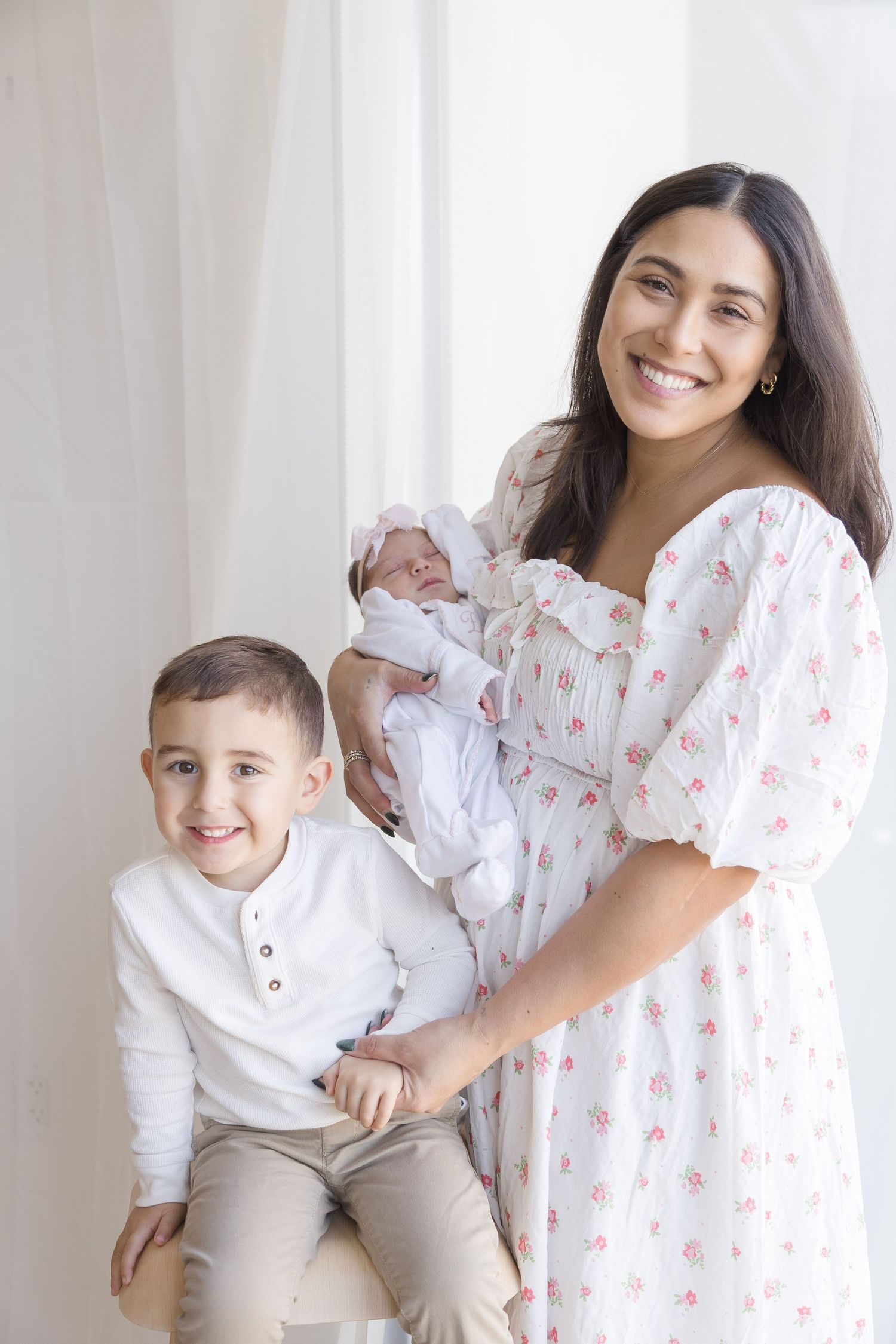 "Mother with newborn and son smiling at the camera in Washington DC home lifestyle session."