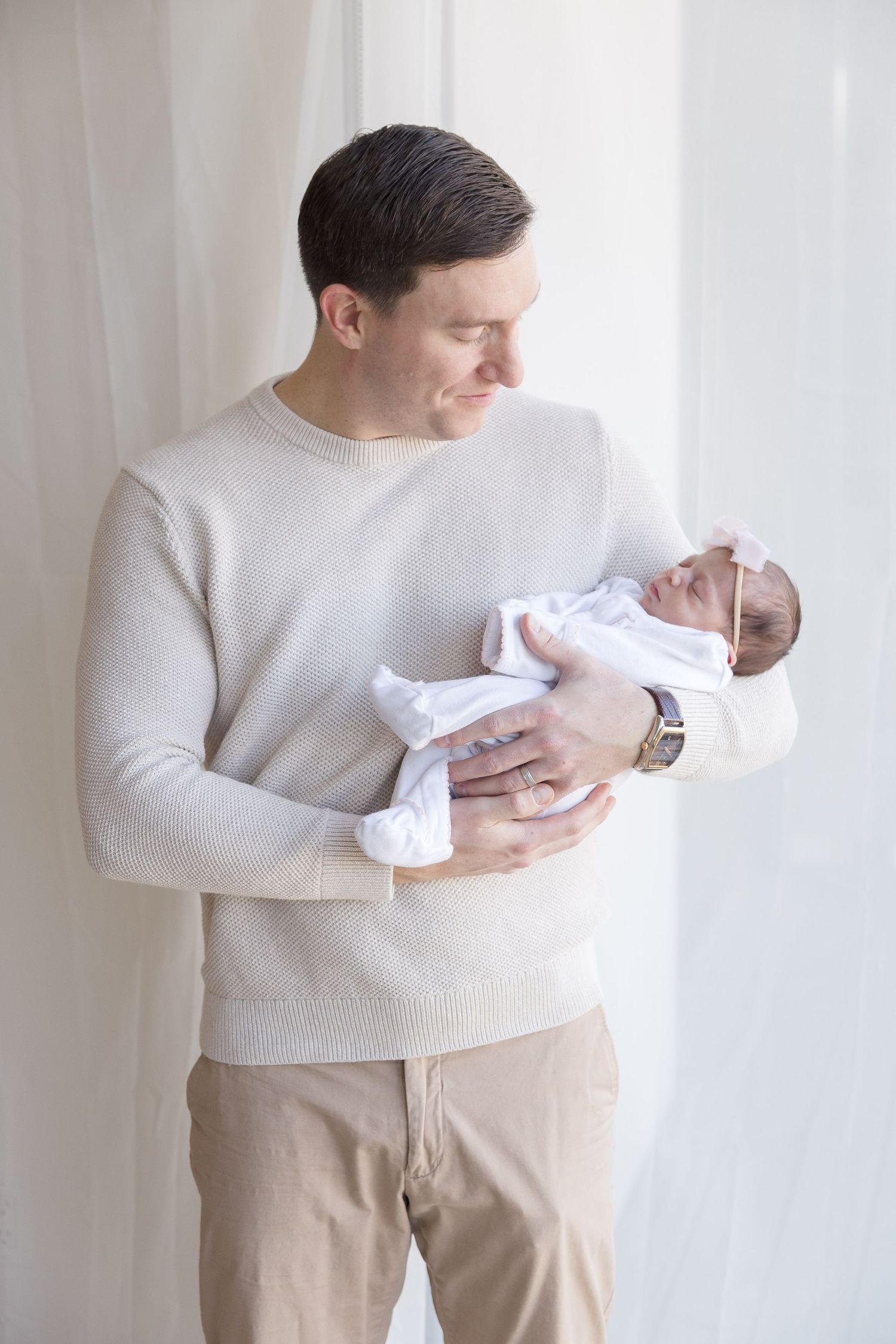 "Father holding sleeping newborn in luxury and elegant Washington DC newborn session."