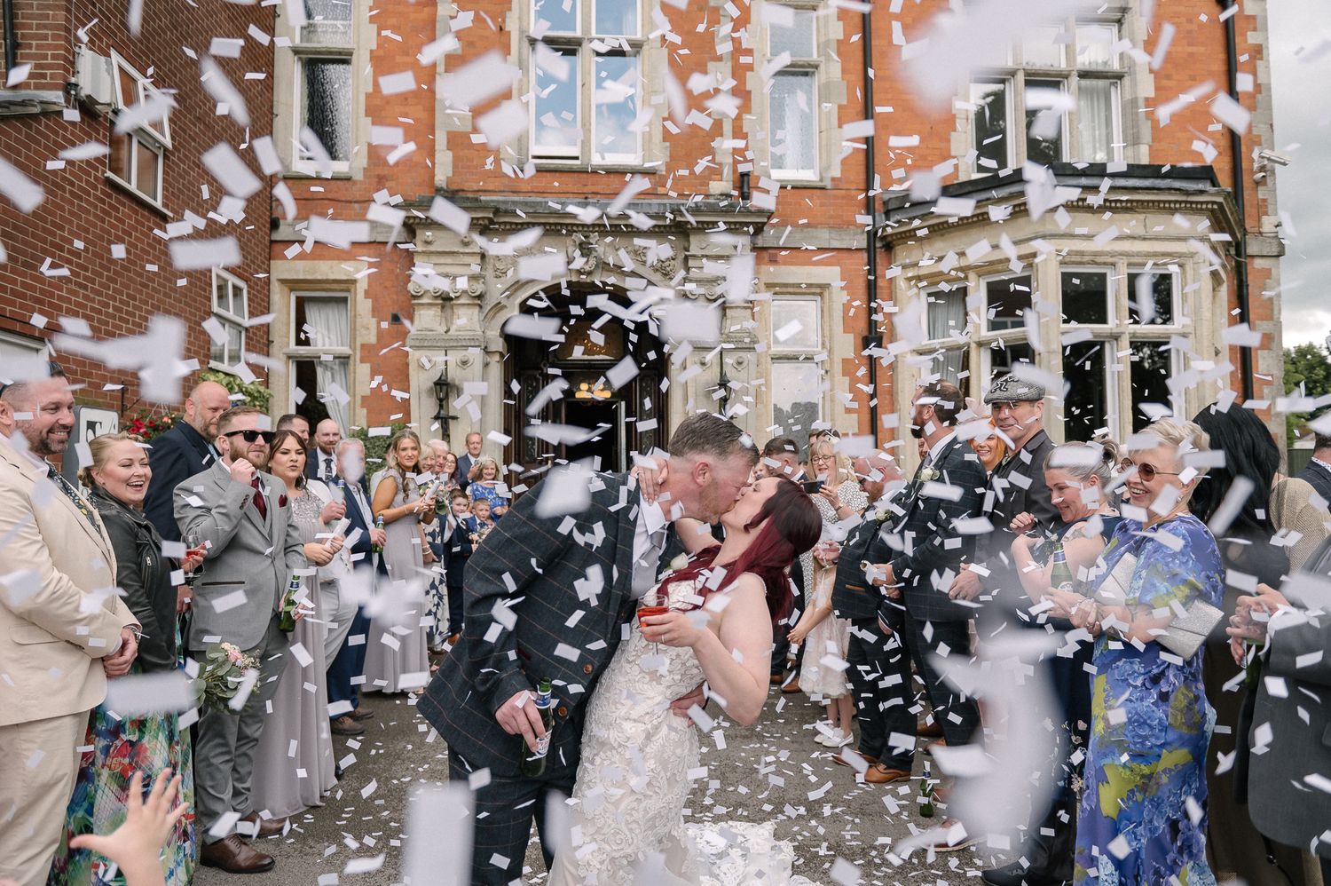 Wedding guests celebrate with confetti outside a church entrance during a joyful celebration.