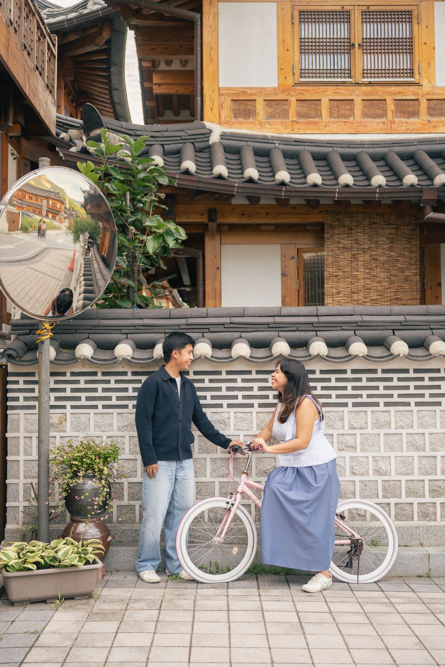 A couple enjoys a romantic moment together on a traditional Korean hanok porch with vintage white bicycle.