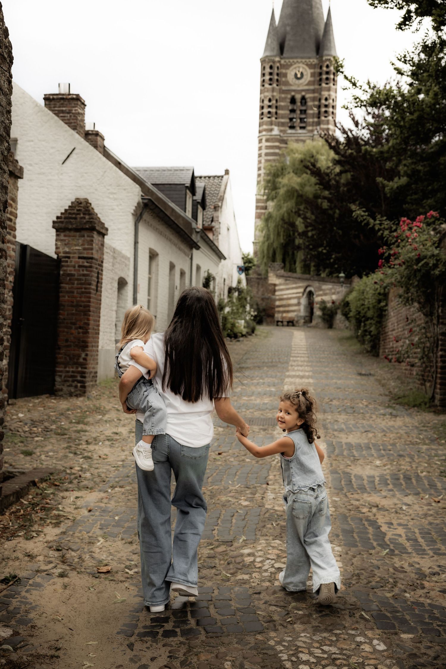 Walking together down a cobblestone street with historic church tower in background.