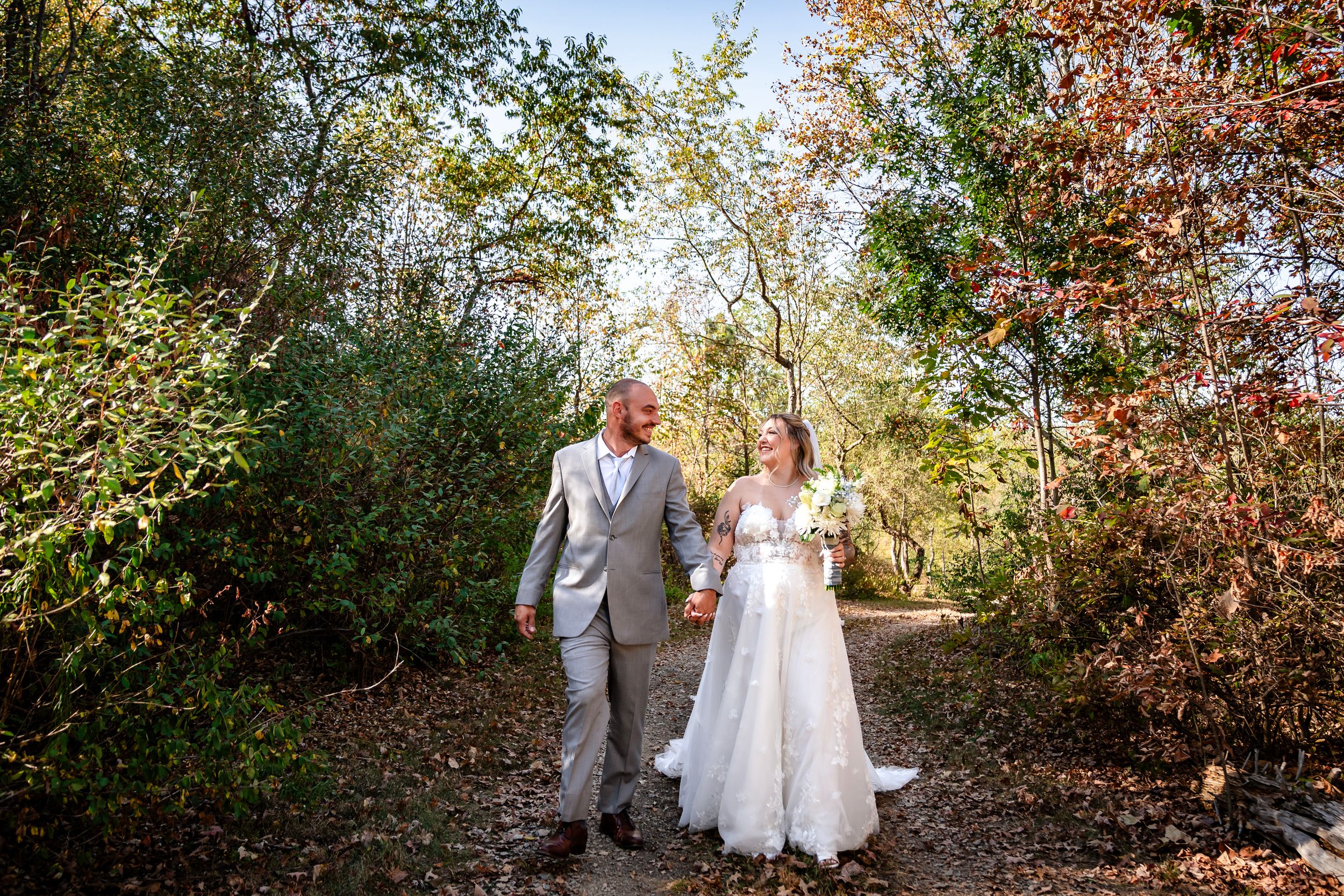Wedding party poses together in a wooded outdoor setting during fall season.