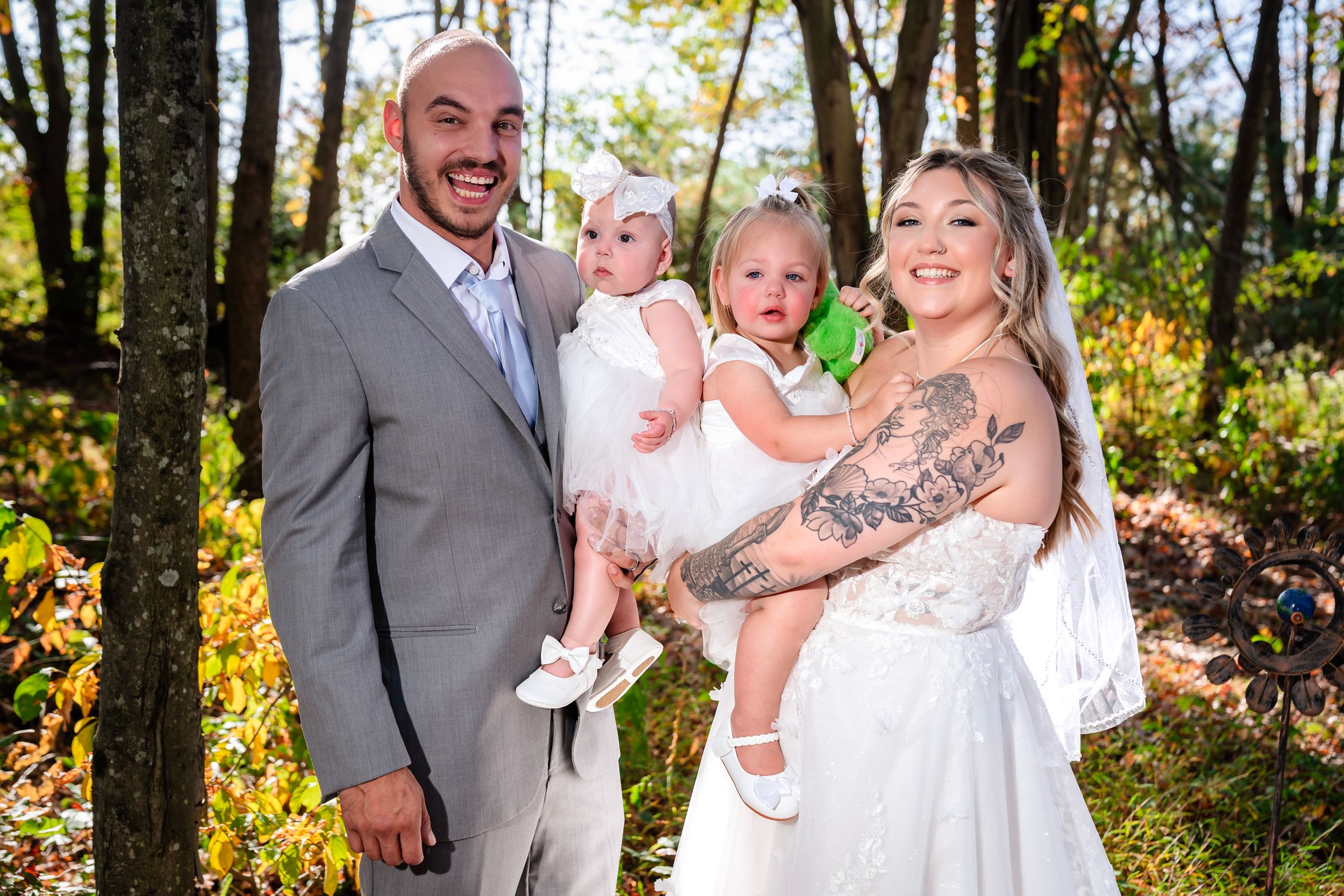 Joyful wedding party photos captured in a sun-dappled autumn forest setting.