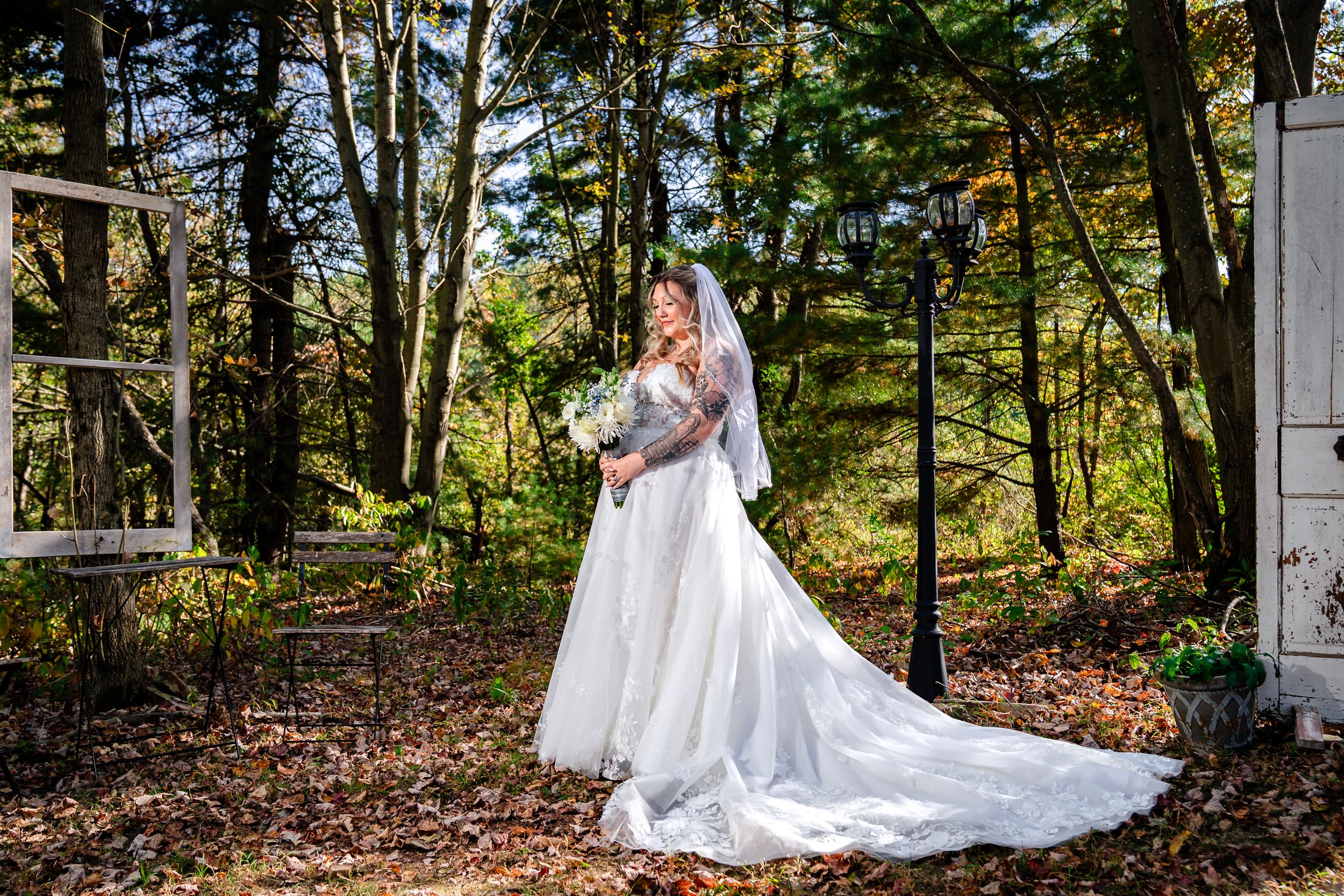 Wedding party poses for portraits in front of rustic white doors surrounded by fall foliage.
