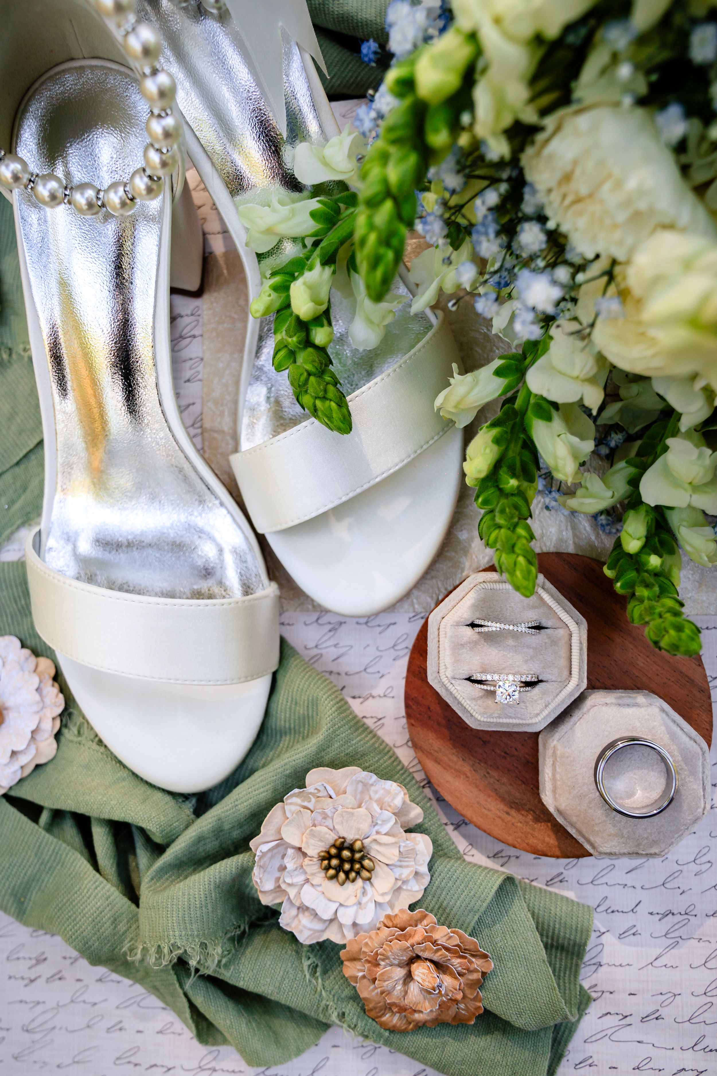 White bridal shoes and floral accessories arranged with elegant bouquet details.