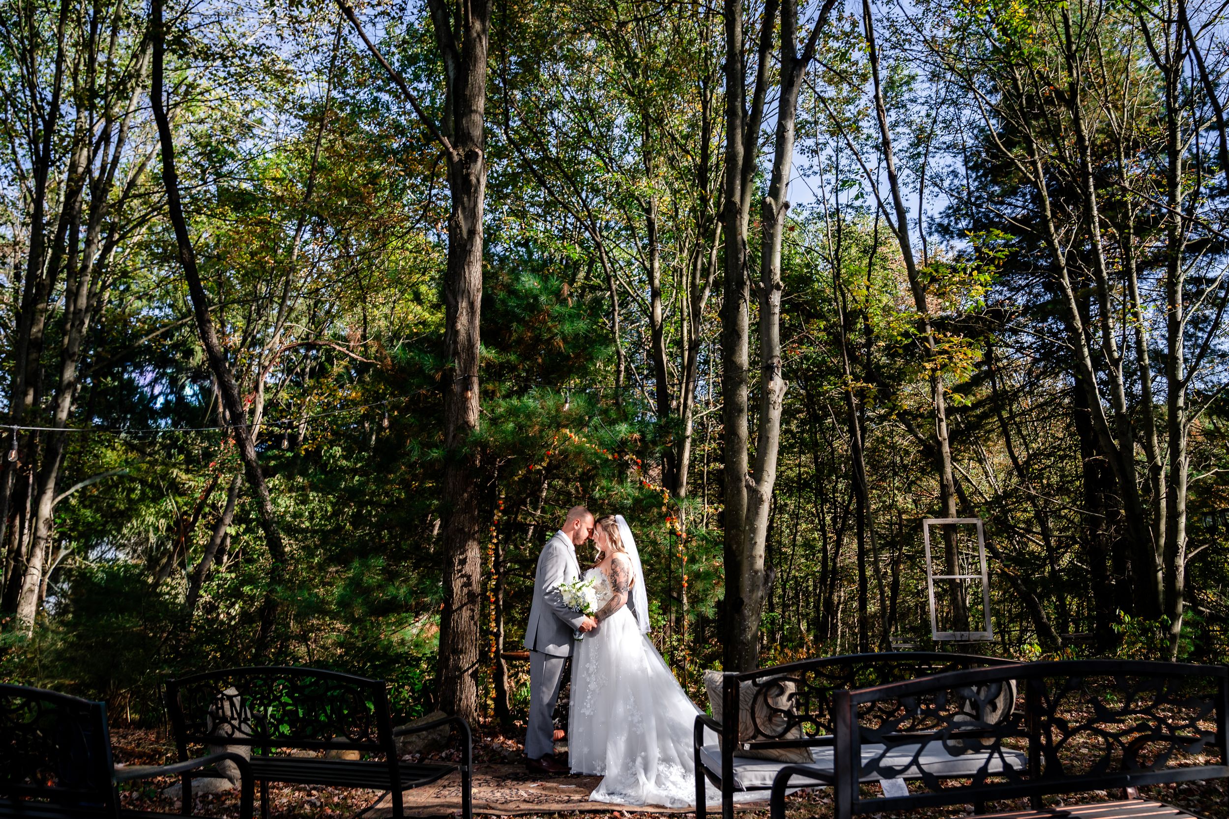 A romantic wedding portrait captured in a serene wooded setting with natural lighting.