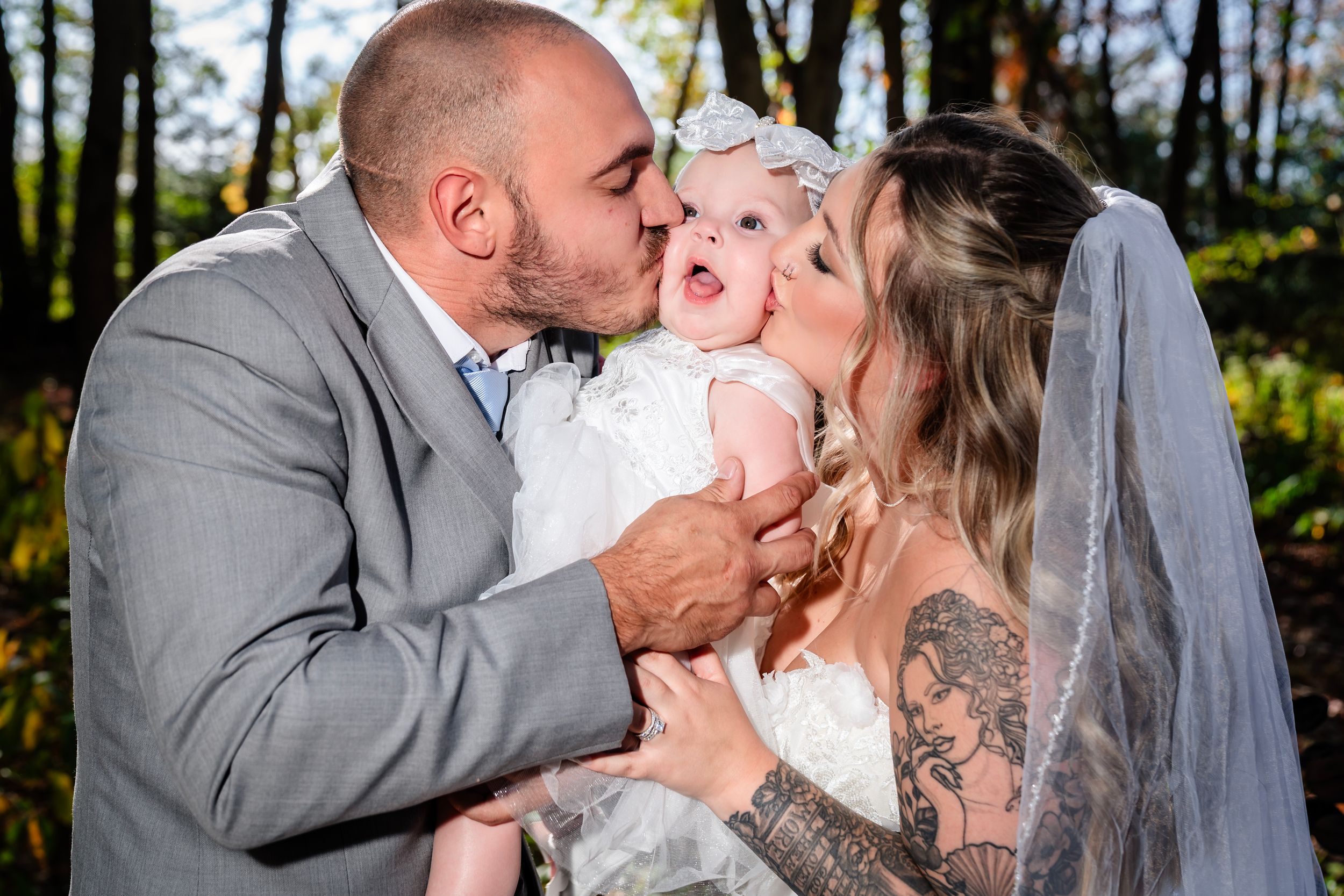 A tender family moment captured during an outdoor wedding photoshoot in a forest setting.