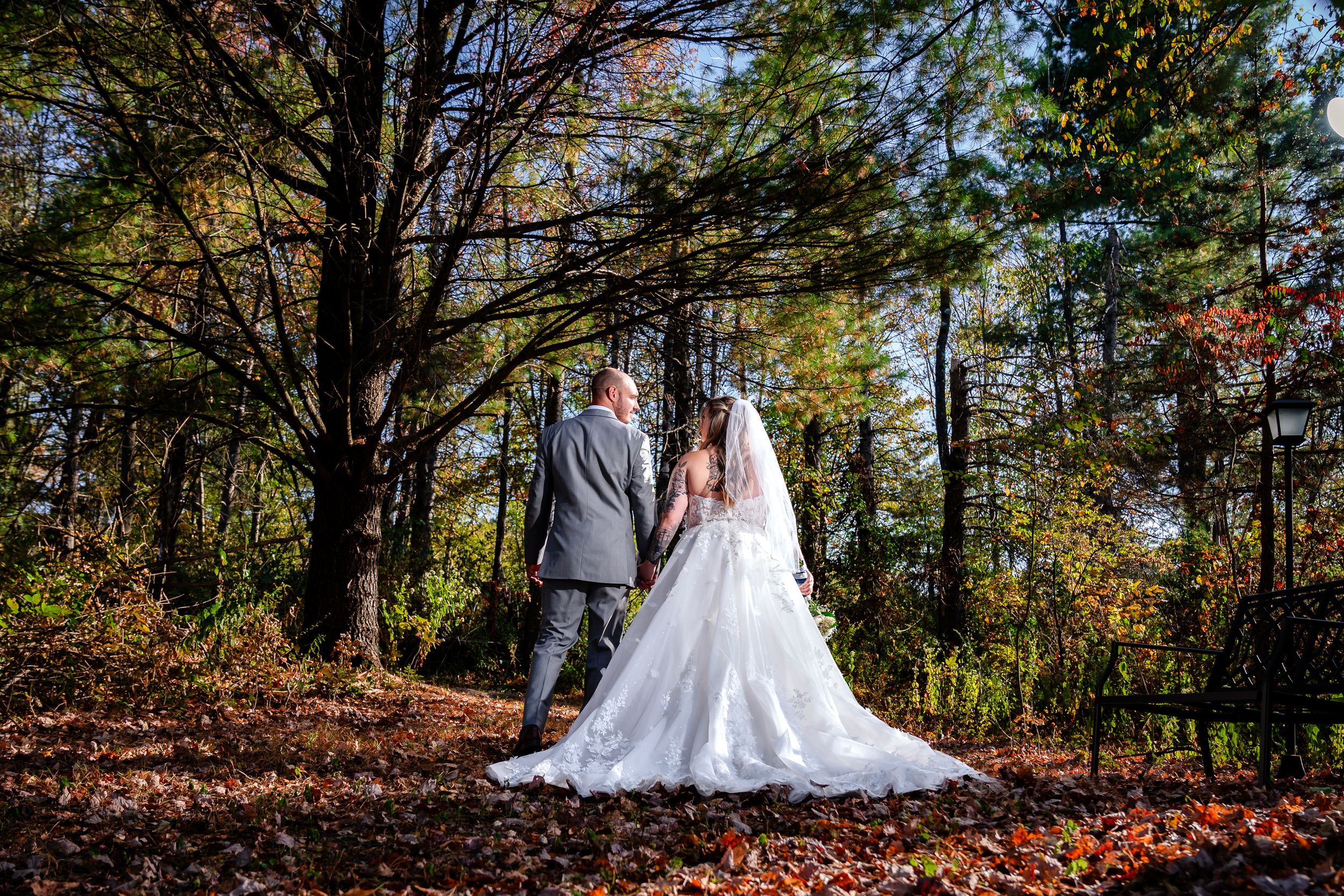 A wedding portrait showcasing a beautiful lace dress train against fallen autumn leaves.
