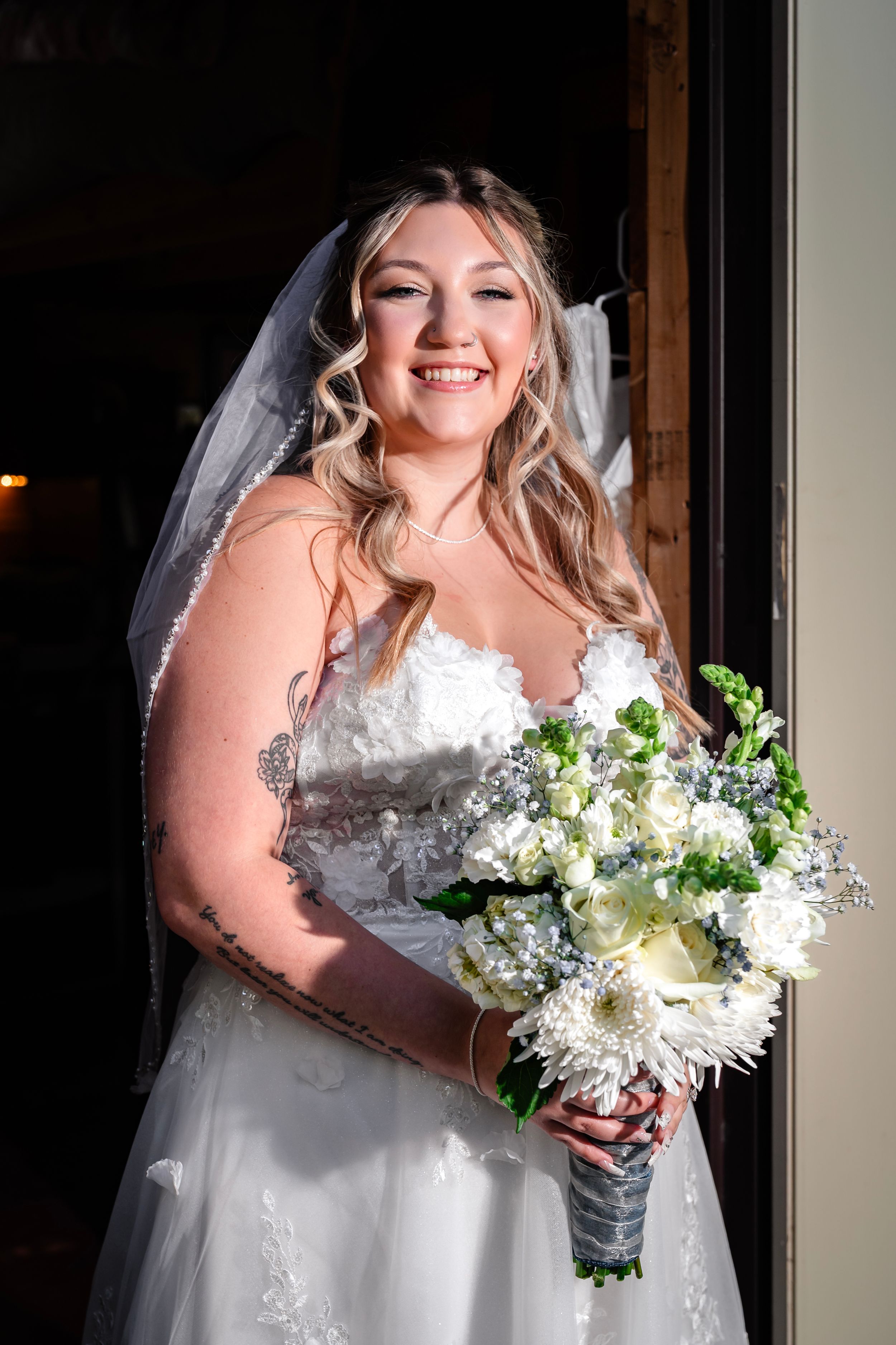 Elegant bridal portrait with white floral bouquet in natural window lighting.