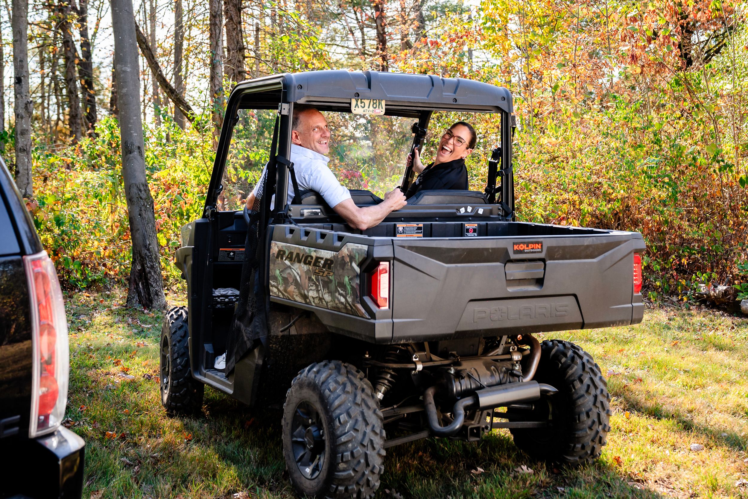 Off-road vehicles parked along autumn forest trail with fallen leaves.