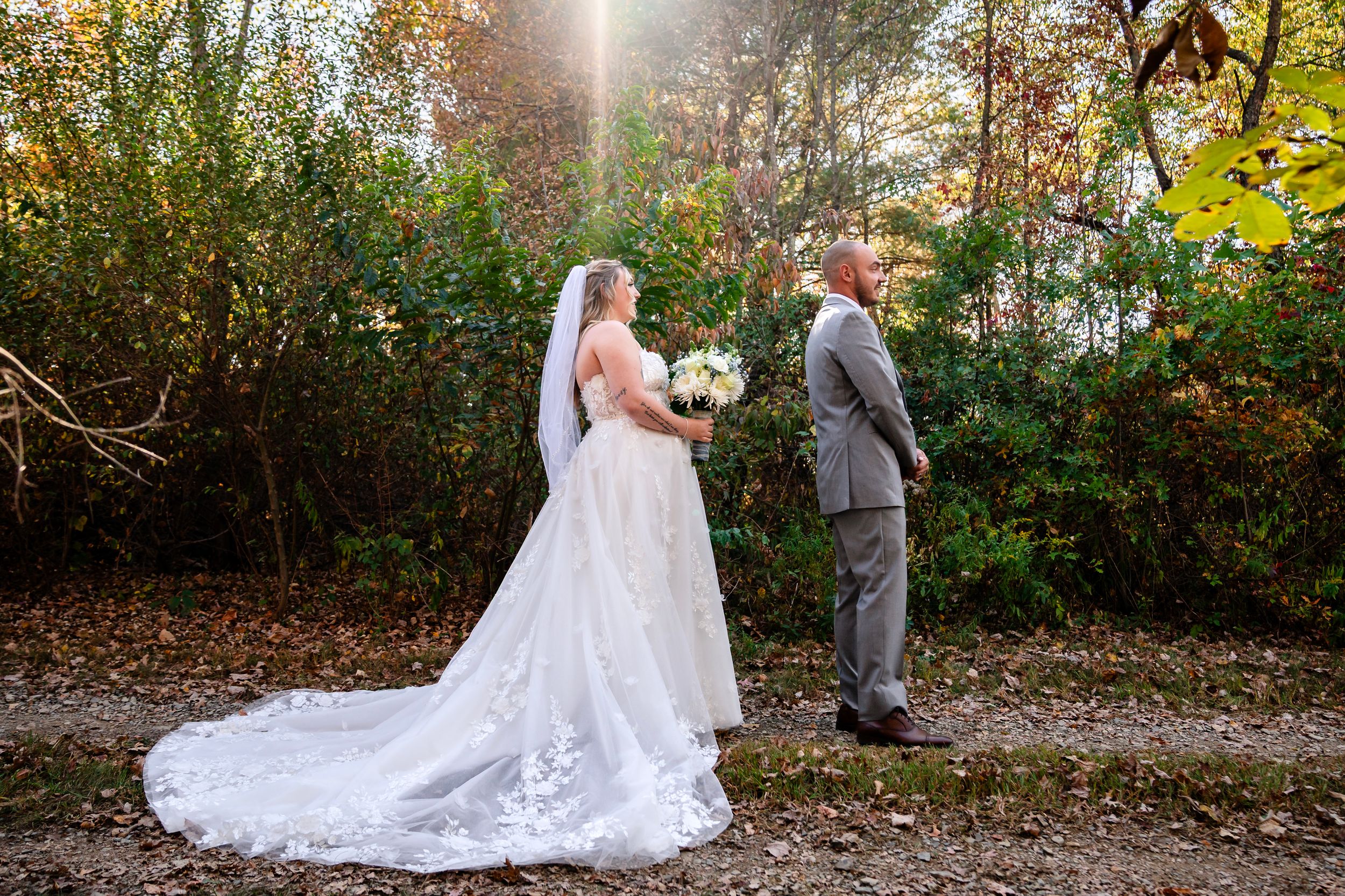 Wedding couple portraits taken on tree-lined path with golden fall foliage.