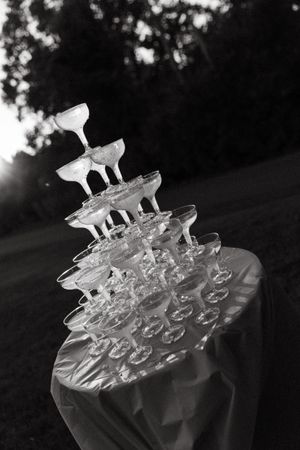 Multiple champagne glasses are stacked in tiers on a dark background creating an elegant display for a special occasion.