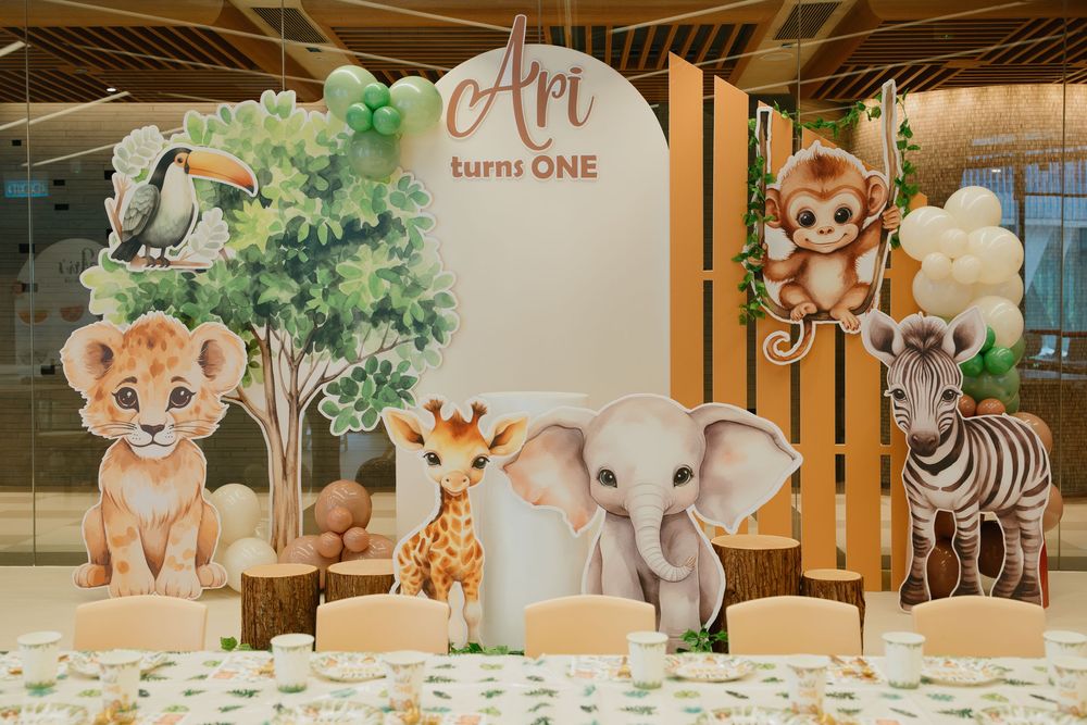 Safari-themed party decor with cartoon animal cutouts and banners adorning a modern indoor space.