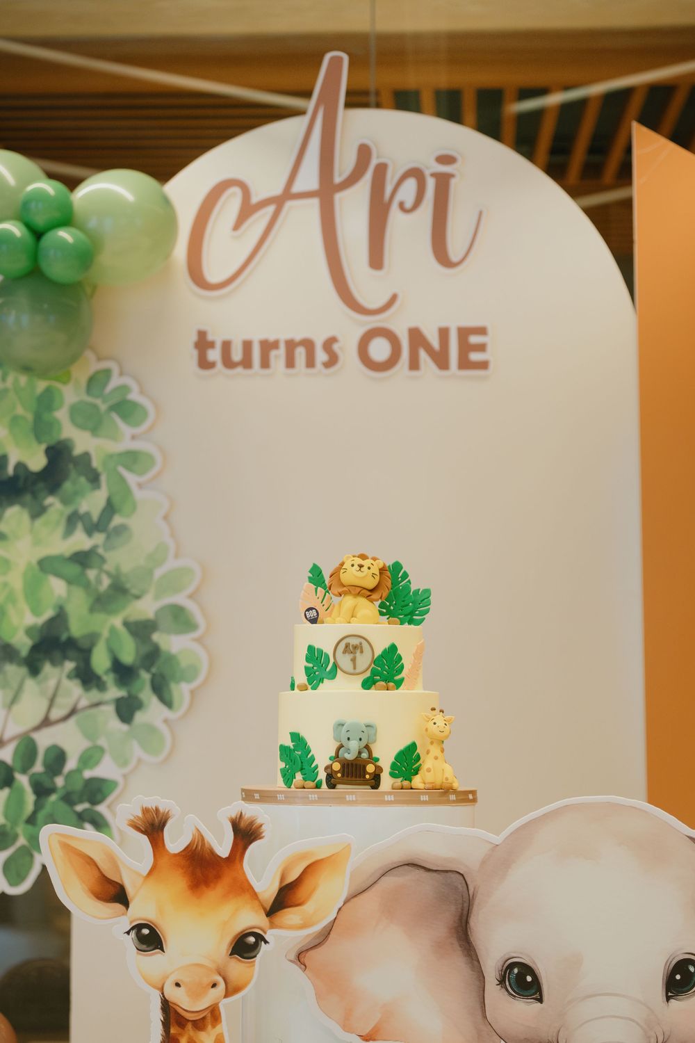 First birthday party decorations with cute giraffe theme featuring balloons and banners in soft pastel colors.