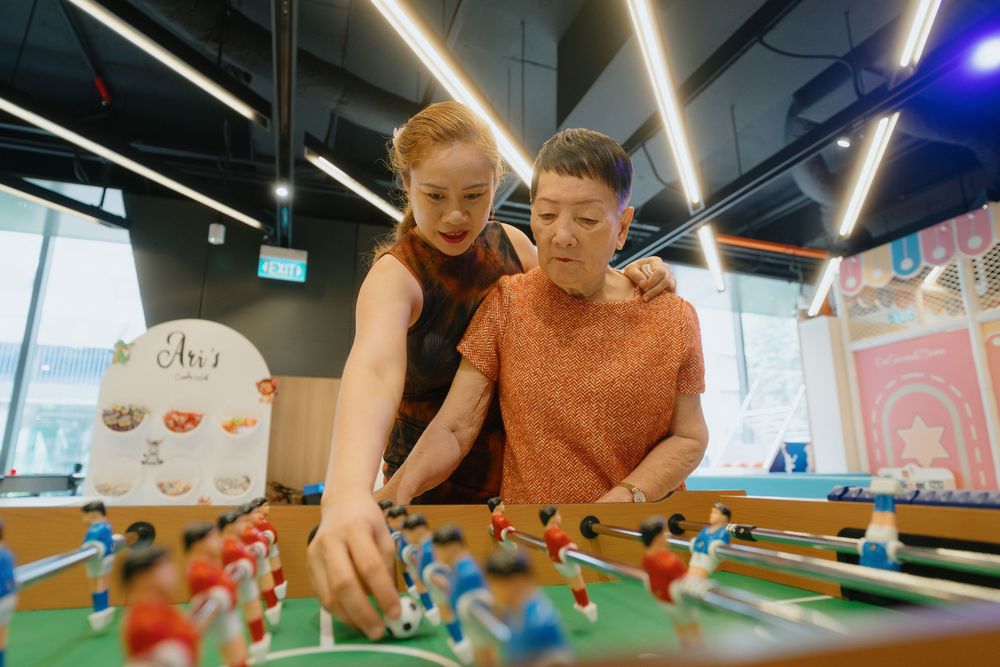 Two people playing foosball together at an indoor entertainment venue with colorful lighting.