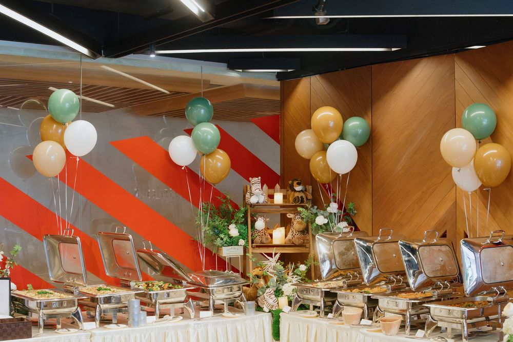 Modern event space decorated with mint green and gold balloons against diagonal orange and wood-paneled walls.