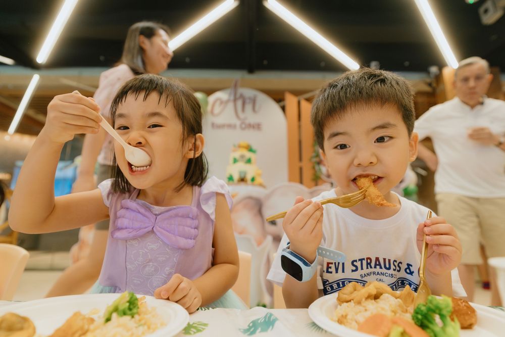 Children sitting at a table enjoying a meal together at what appears to be a birthday party or celebration.