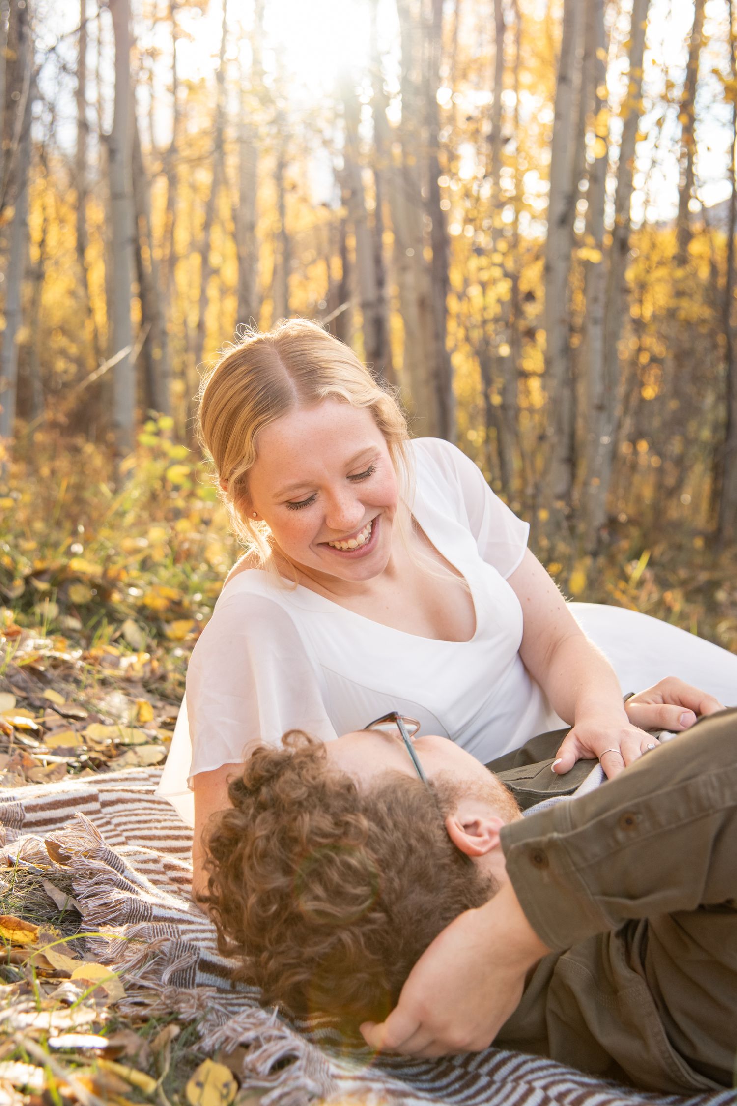 Intimate couples photo session in Vail Colorado with a couple laying down looking at each other with the golden light shining through trees