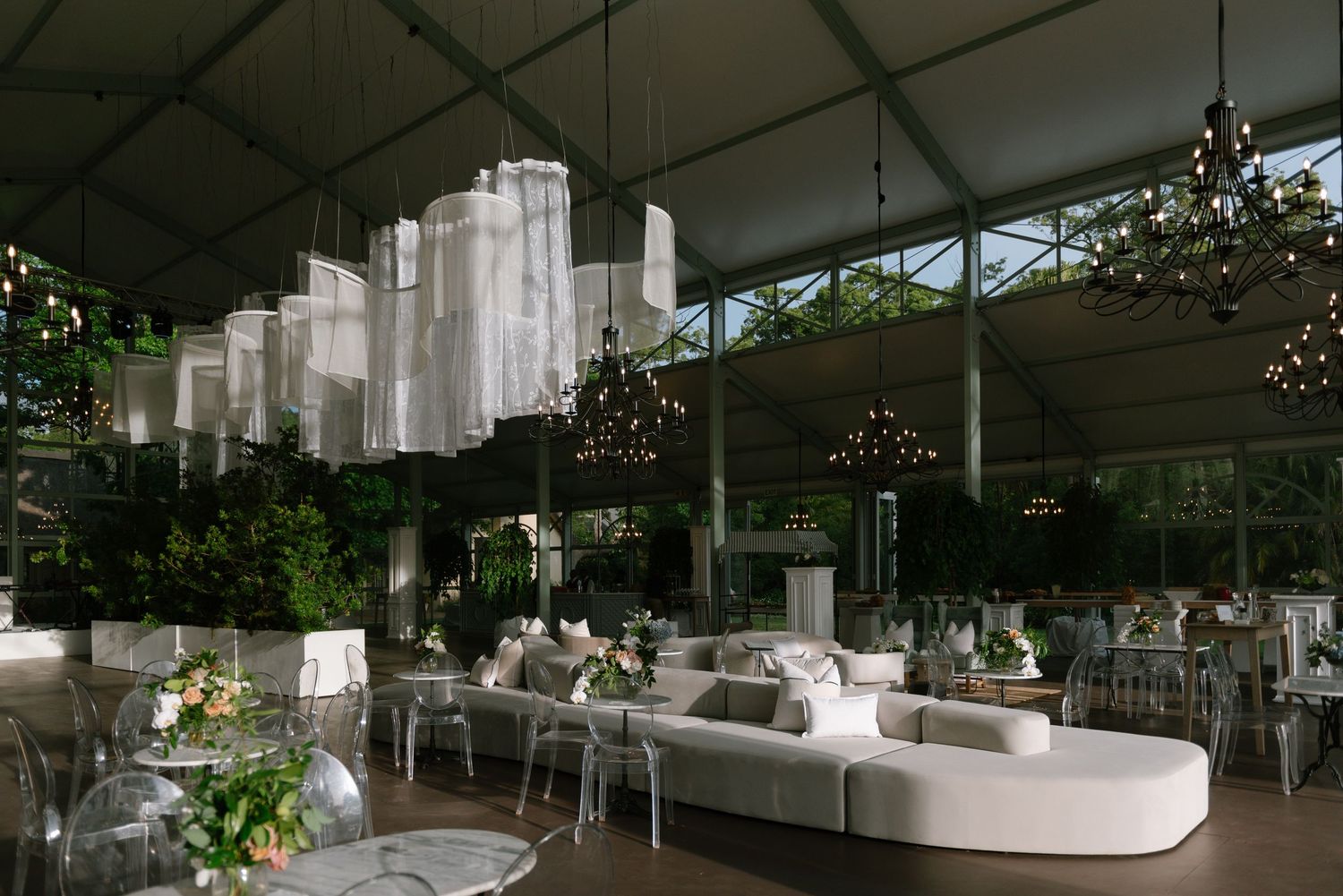 Modern outdoor event space with white tent canopy and elegant lounge furniture arranged in a garden setting.