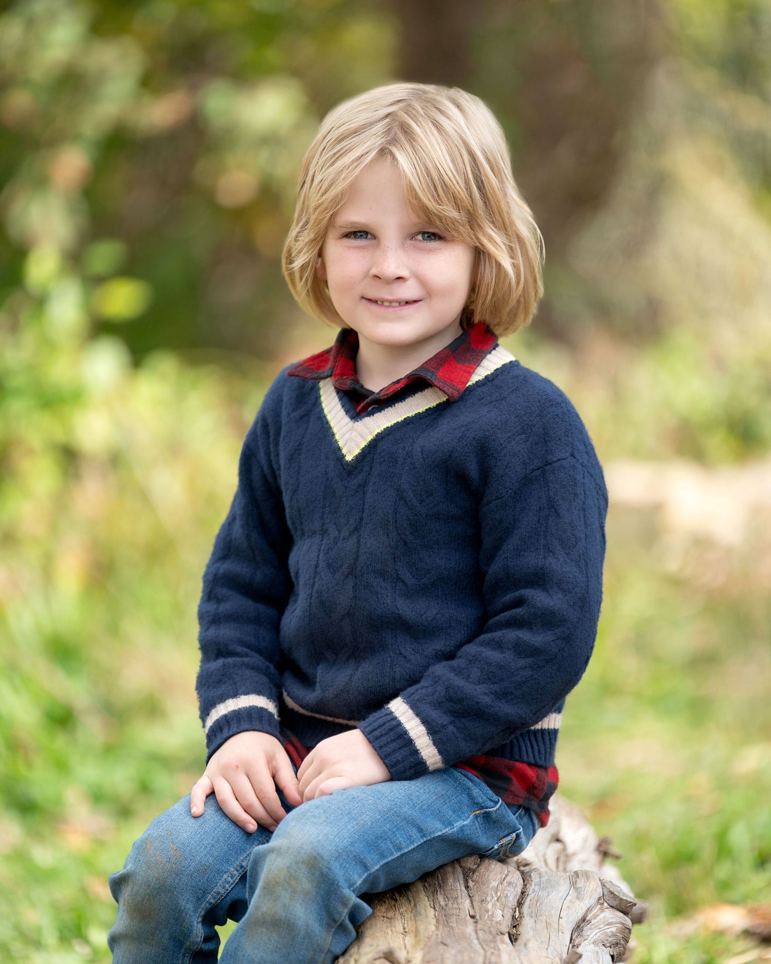 Young child in floral dress smiling with windswept hair against green background.