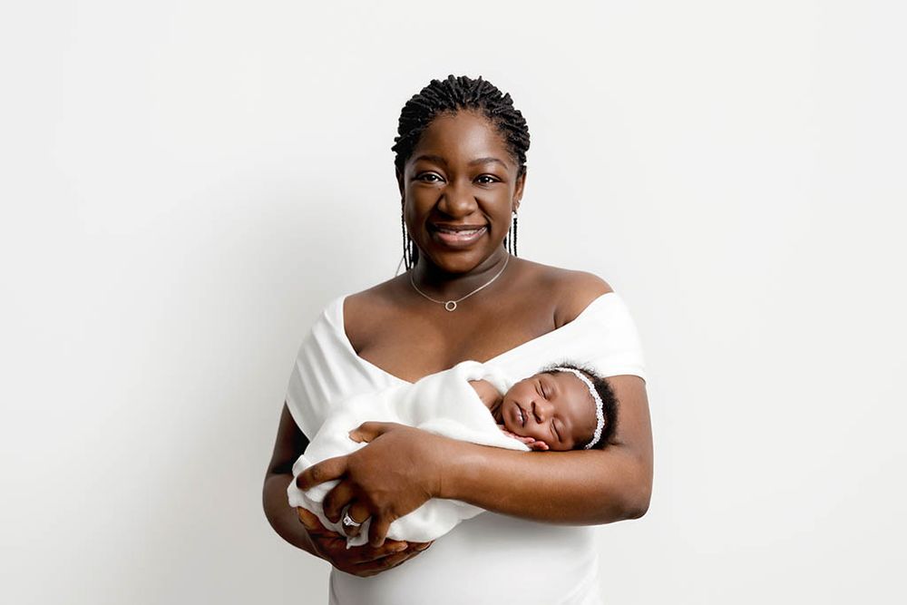 Smiling mom holding sleeping baby girl in her home newborn photography session in Hemet.