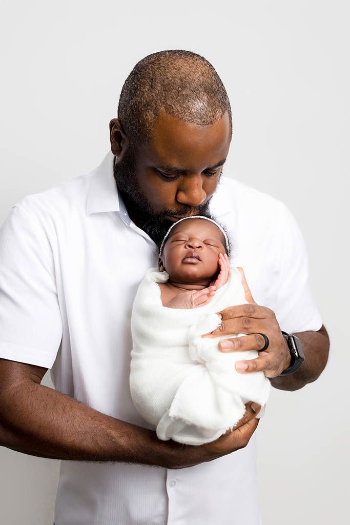 Newborn father daughter photo of a dad kissing his newborn baby girl.