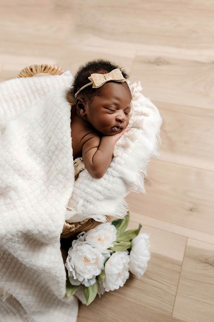 Newborn baby girl sleeping in a basket prop with white flowers, by newborn photographer in Hemet CA.