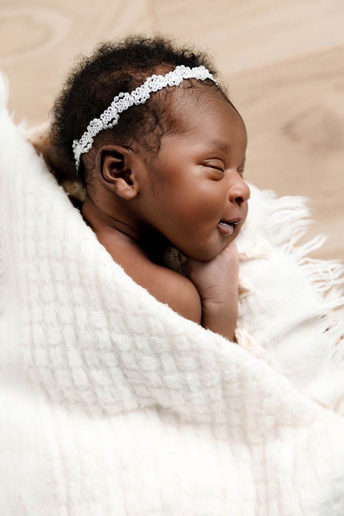 Sleeping newborn baby girl wrapped in a soft white blanket, by in-home newborn photographer near Hemet.