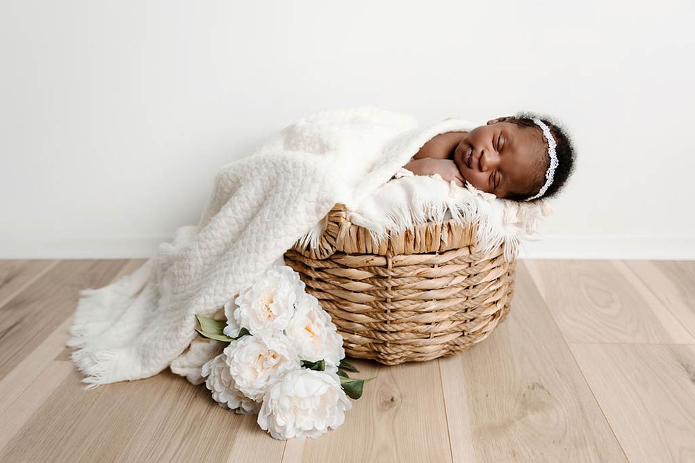Newborn baby sleeping in a basket prop by professional photographer in Hemet.