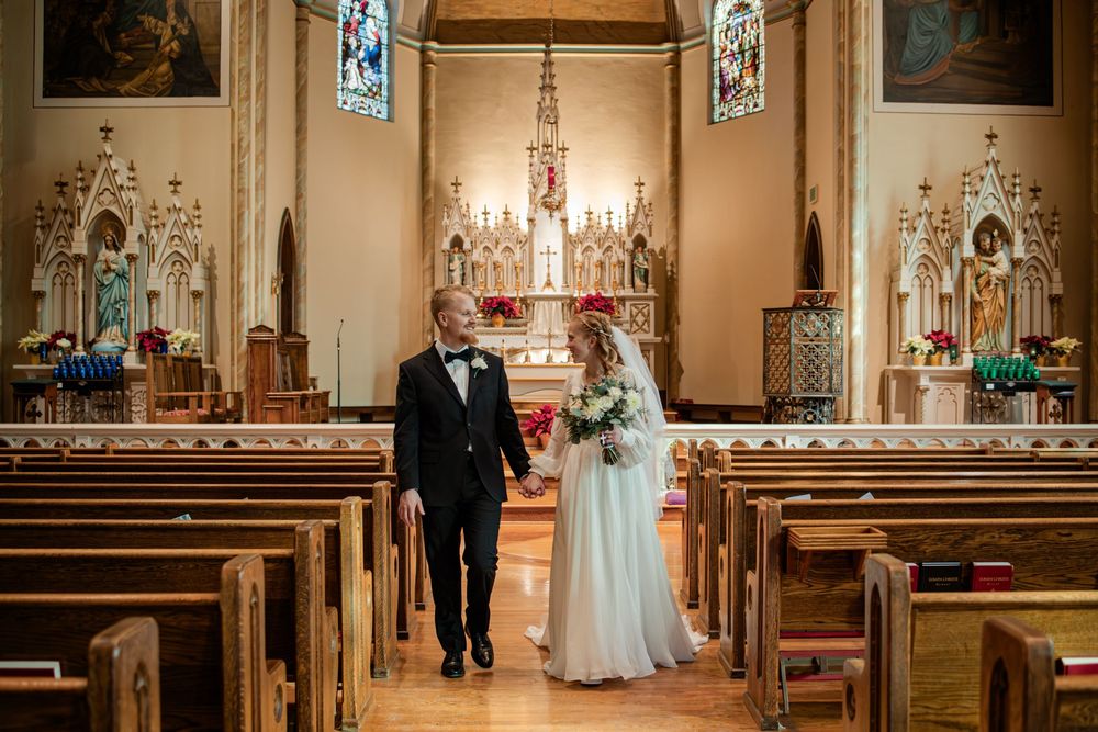 Bride and groom walking down the aisle of an ornate church after their wedding ceremony.