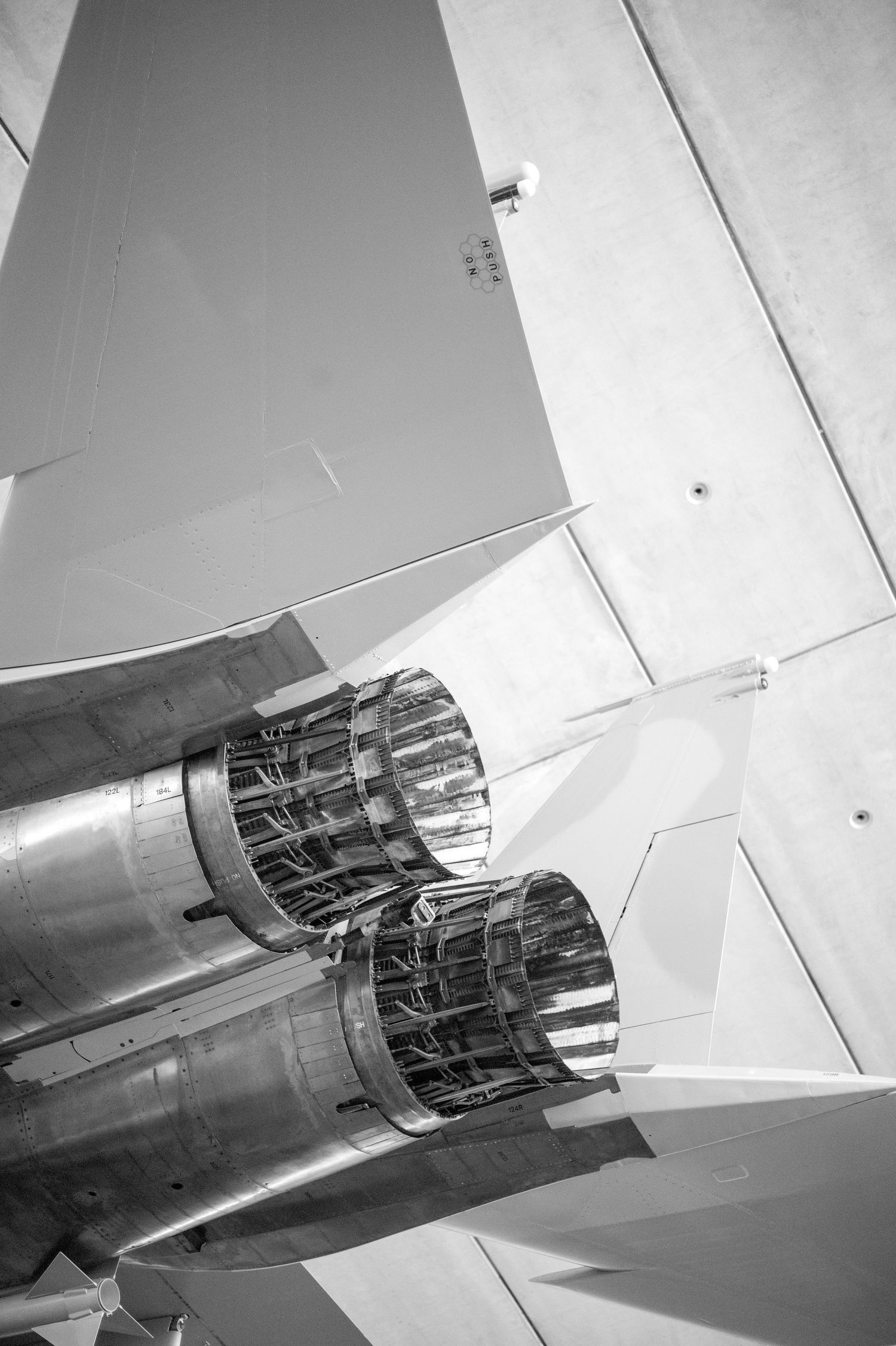 Black and white close-up of twin jet engine exhausts on a military fighter aircraft viewed from below.