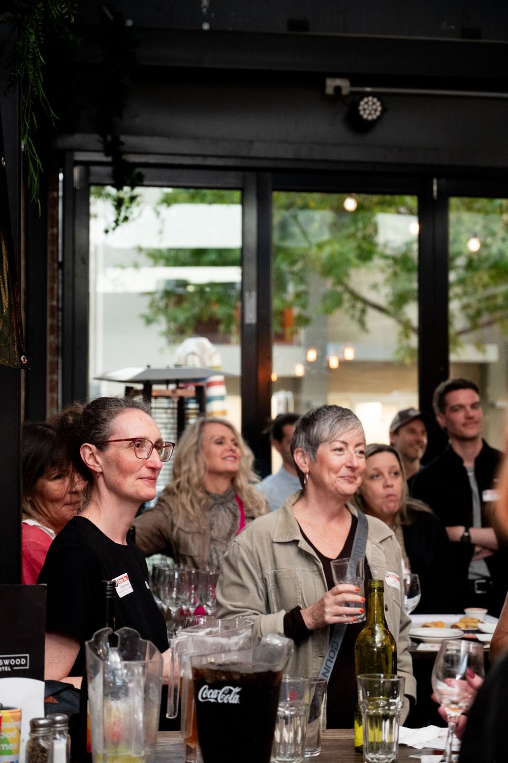 A group of people socializing at an indoor event with wine and soft drinks.