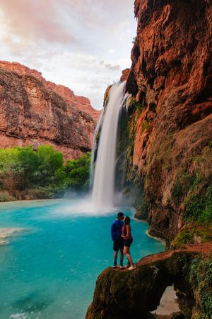 A couple pose on a rock ledge in Havasu Falls in the Havasupai Indian Reservation in the Grand Canyon.