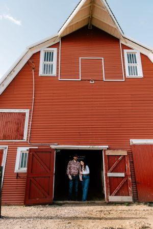 A couple pose in the family ranch horse barn in Hosper, Iowa for their engagement photos.
