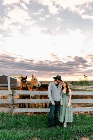 A couple pose in the family ranch horse barn in Hosper, Iowa for their engagement photos.