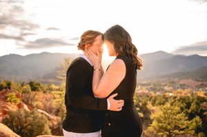 Two women share a romantic moment at sunset with mountain landscape backdrop at Garden of the Gods.