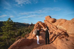 Couple exchanging vows atop red rock formations at Garden of the Gods, Colorado, under a blue sky.
