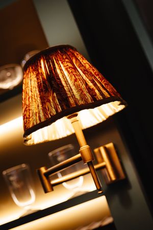 Elegant wall sconce lamp with warm golden light and ornate pleated shade in rich brown tones.
