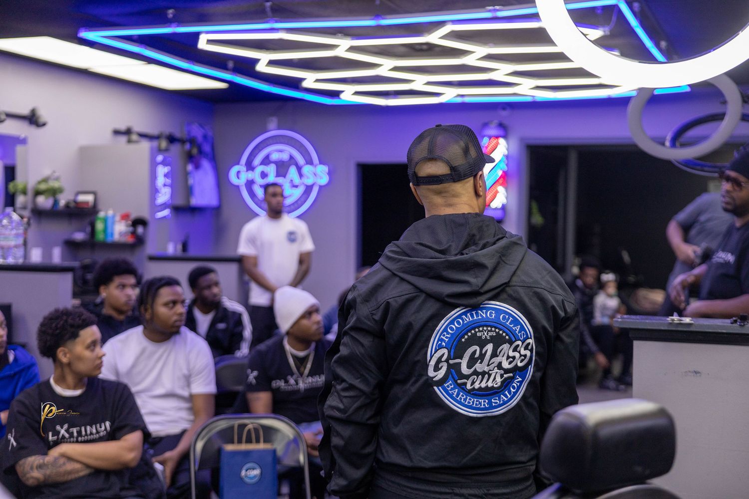 Group of young men gathered inside a C-Class Club barbershop for a community meeting or event.