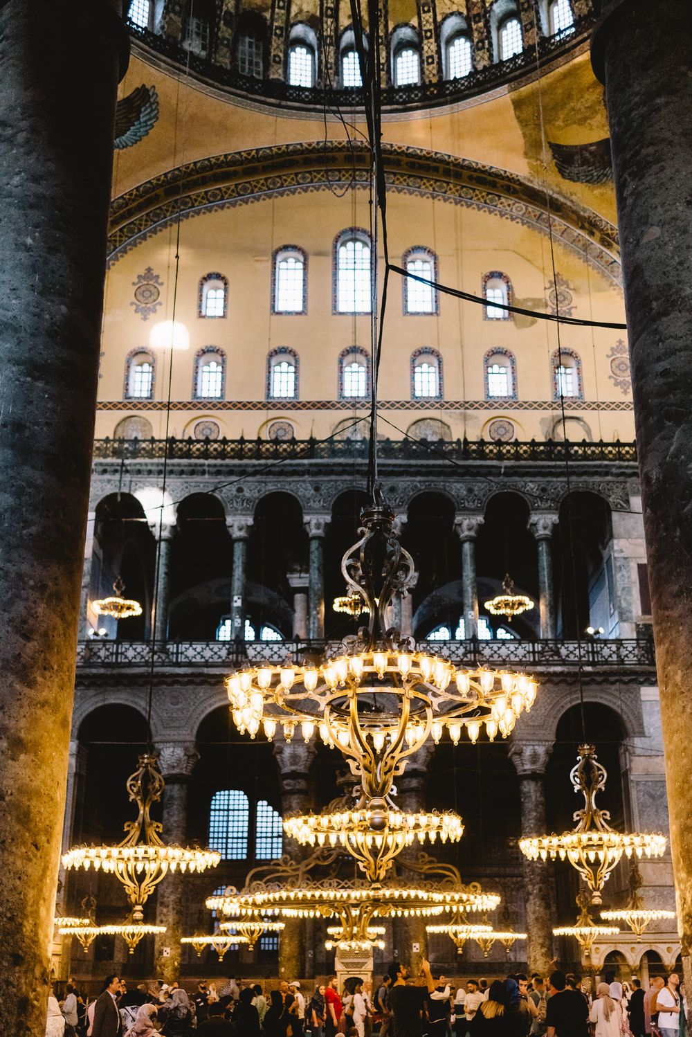 Interior of Hagia Sophia featuring ornate chandeliers, arched galleries, and Byzantine architecture in Istanbul, Turkey.