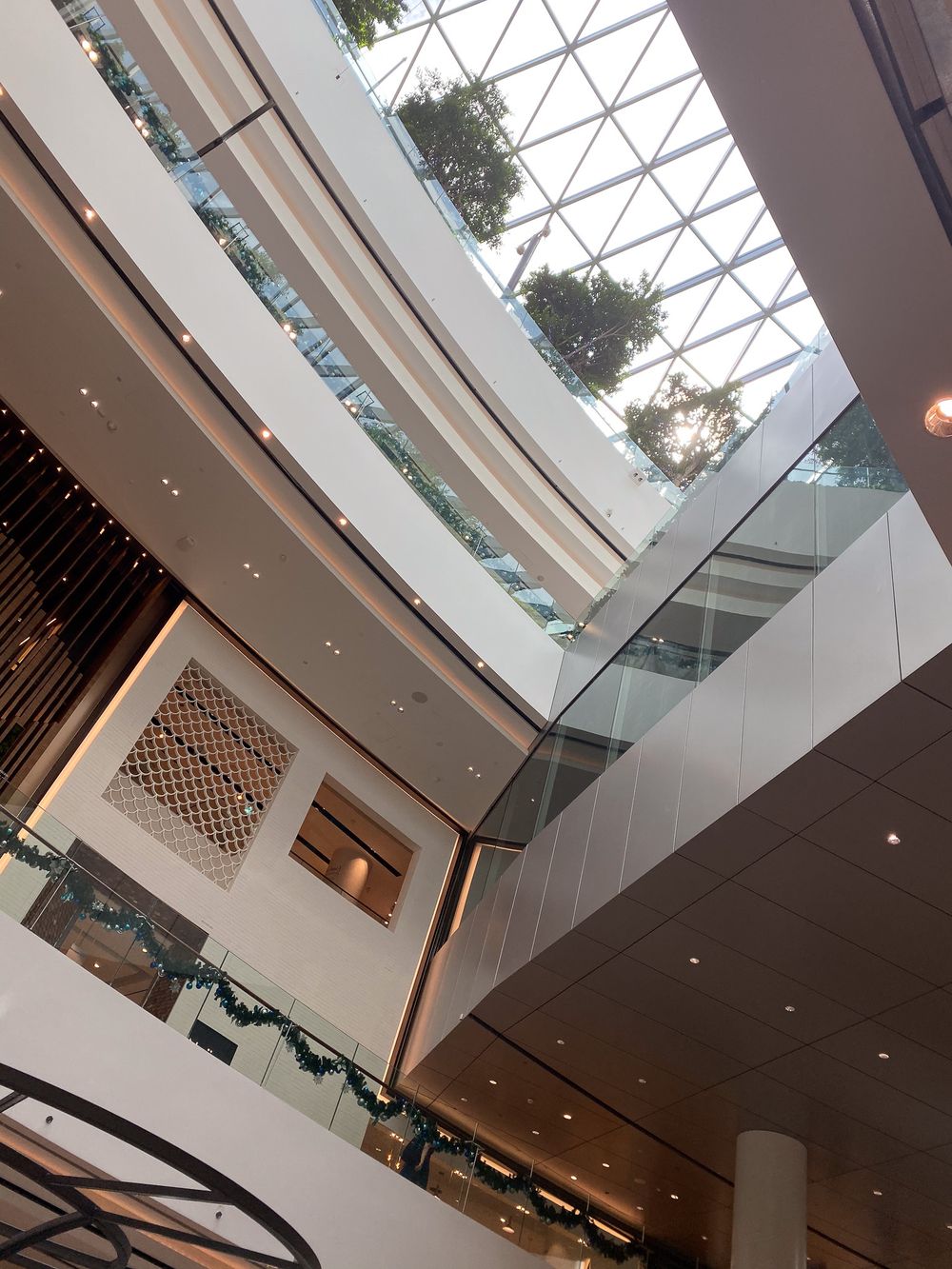Changi Jewel, Singapore. Bright multi-story mall atrium with glass ceiling, curved balconies, and natural light flooding interior.