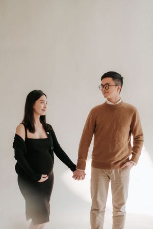 Minimalist photo series of a couple in black and brown outfits posing playfully against a white background一組極簡主義風格的照片，一對身穿黑色和棕色服裝的情侶在白色背景前擺出