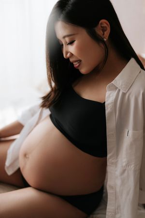 A series of intimate maternity photos showing a pregnant woman in black and white clothing against a light background.一組溫馨的孕婦照，照片中一位孕婦身穿黑白服裝