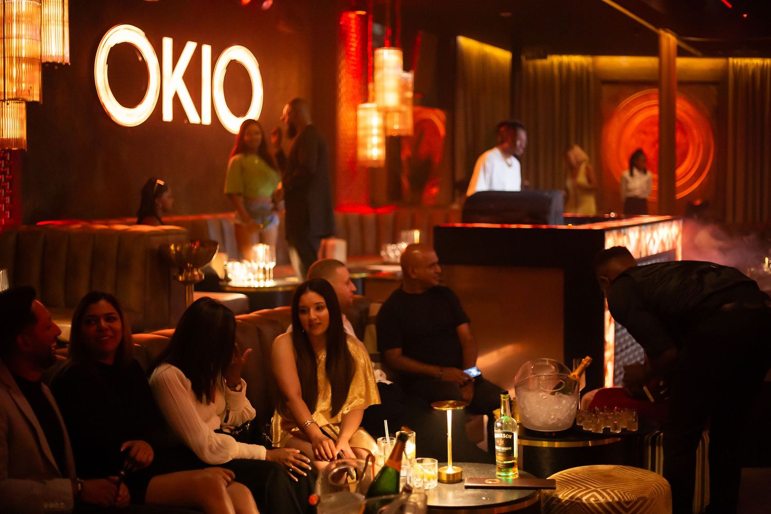 Guests socializing at OKIO nightclub, featuring warm ambient lighting and elegant lounge seating.