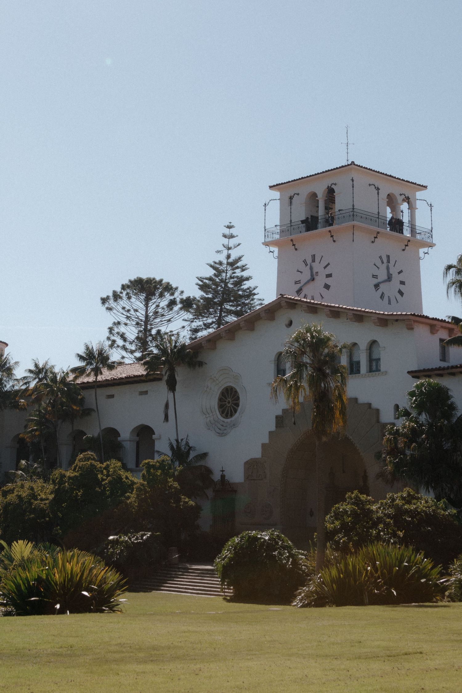 Santa Barbara County Courthouse white Spanish Colonial Revival building with clock tower surrounded by lush gardens and palm trees.